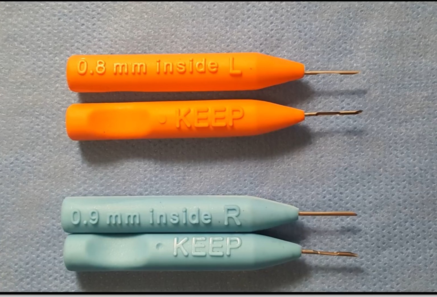 Orange and pale blue K.E.E.P. graft-placement instruments with their fine metal tips